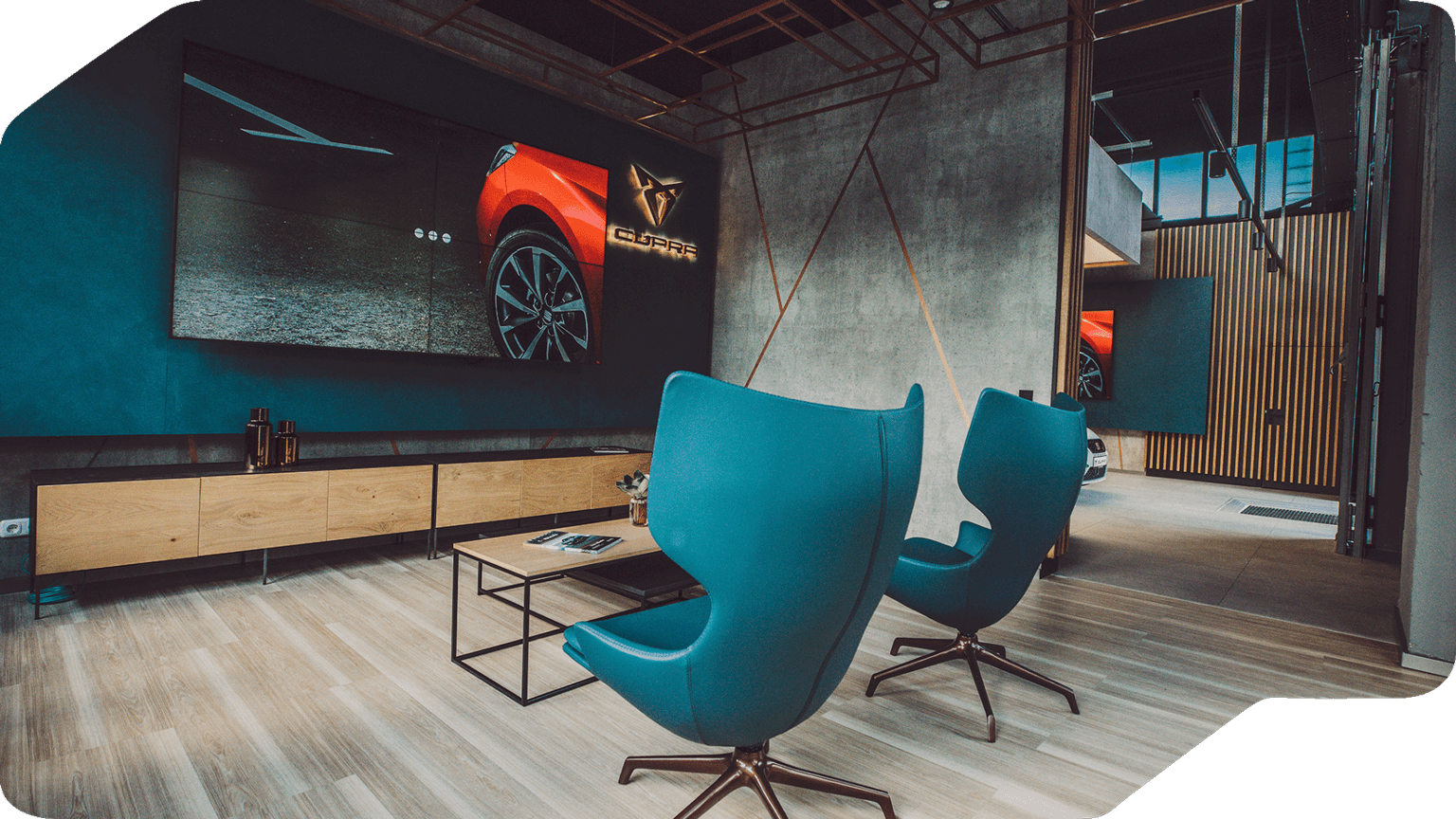 Lounge-Bereich der CUPRA Garage Hamburg mit großen Bildschirmen, CUPRA Branding und modernen Sitzmöbeln